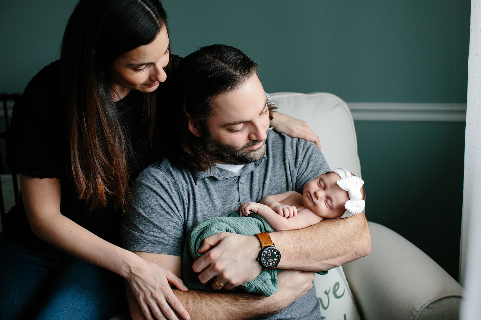 in home newborn photography by Angie Menos - couple with new baby in chair